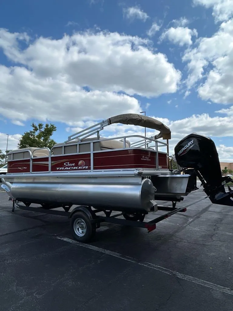 Slide: The Image of 2025 Sun Tracker Party Barge 18 DLX pontoon boat on trailer under cloudy sky. - 4