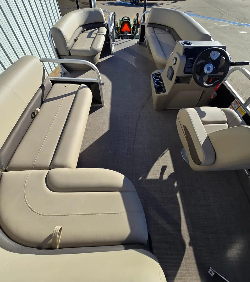 Slide: The Image of 2025 Sun Tracker Party Barge 16 DLX interior with beige seating and steering console. - 6