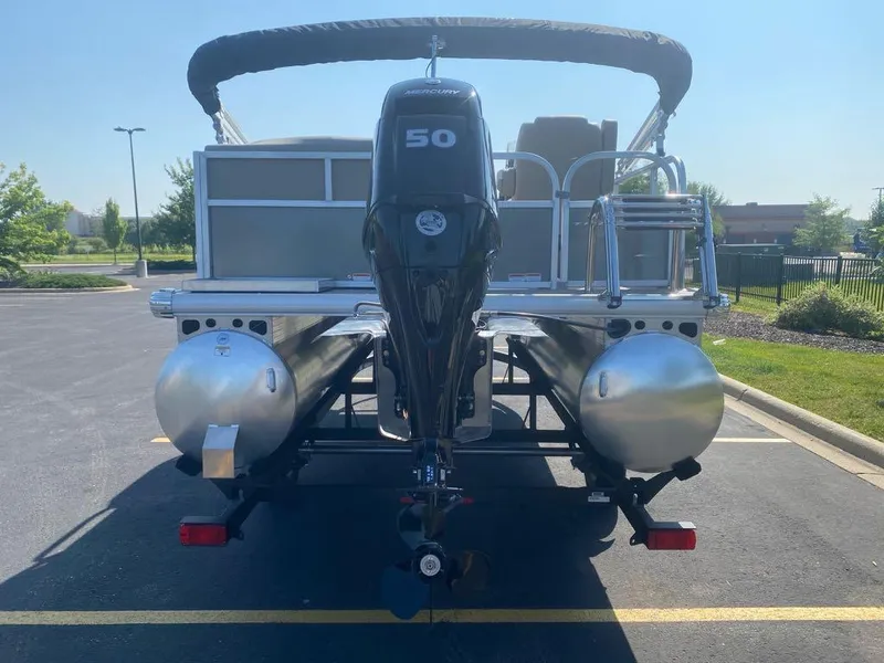 Slide: The Image of 2025 Sun Tracker Party Barge 16 DLX pontoon boat, rear view in parking lot. - 2