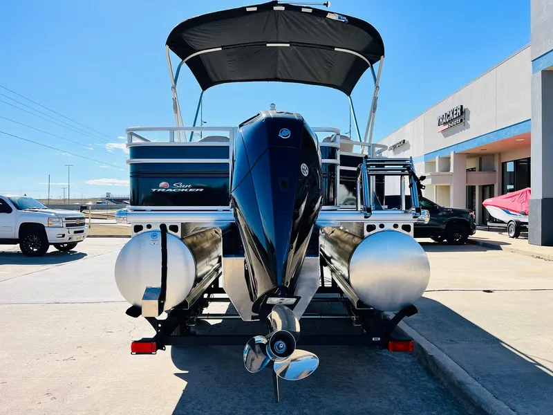 Slide: The Image of 2025 Sun Tracker SportFish 22 XP3 pontoon boat with outboard motor, parked outdoors. - 6