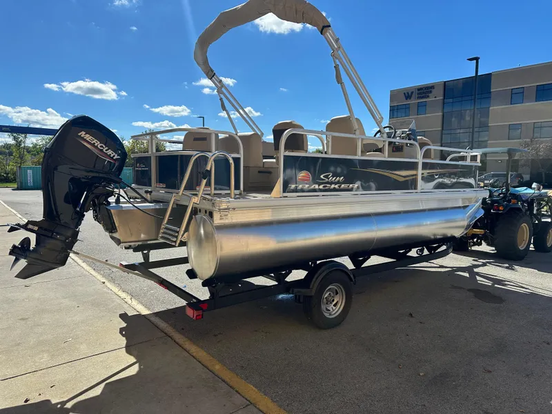 Slide: The Image of 2025 Sun Tracker Bass Buggy 18 DLX pontoon boat with Mercury outboard motor on trailer. - 2