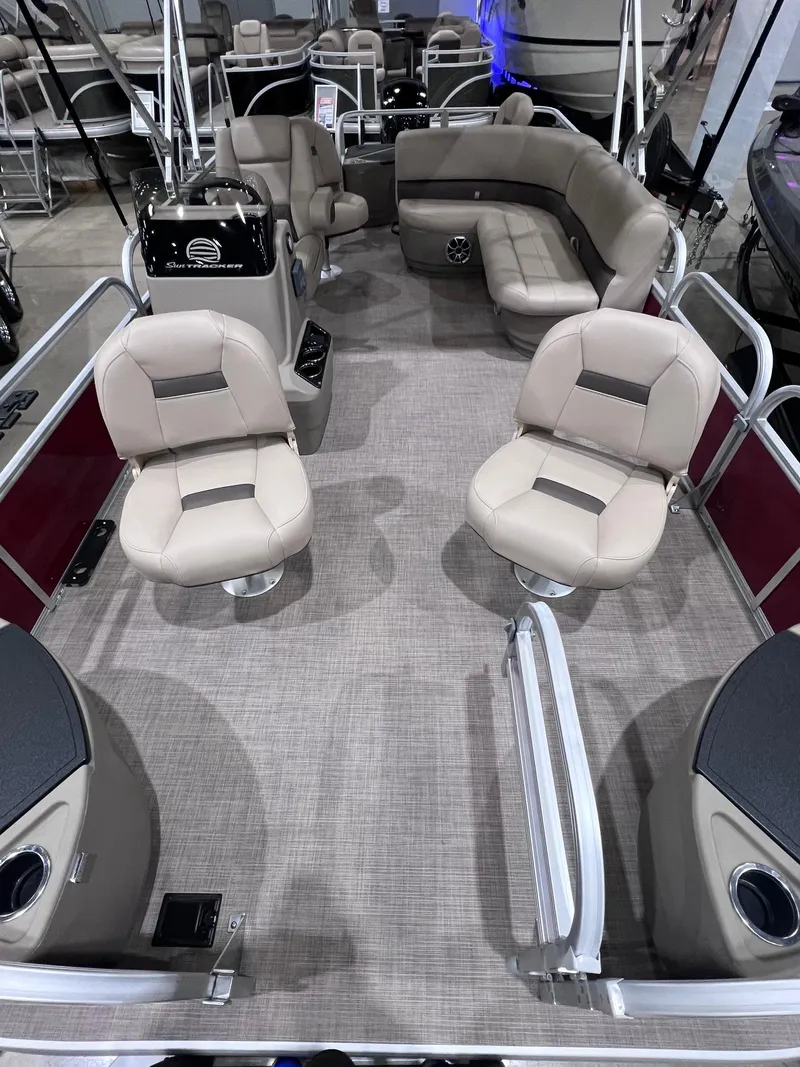 Slide: The Image of 2025 Sun Tracker Bass Buggy 18 DLX pontoon boat interior with beige seating and spacious layout. - 2