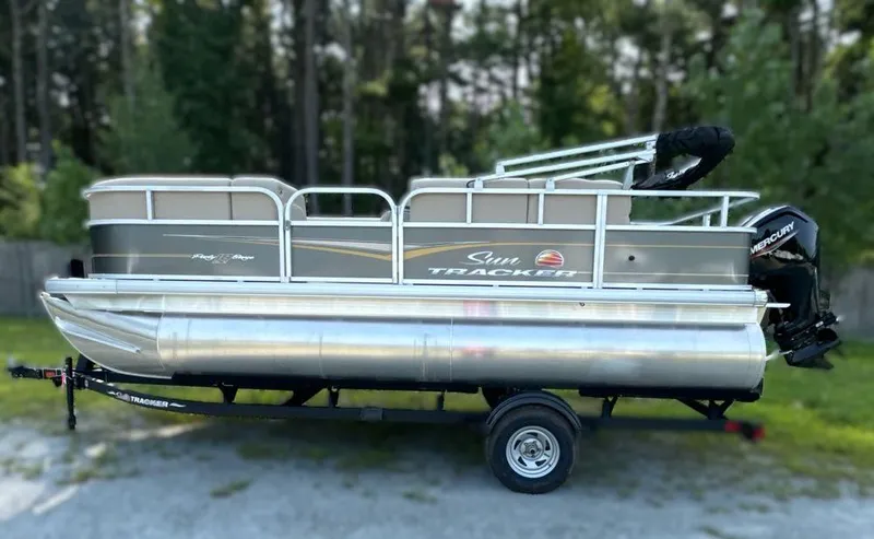 The Image of 2025 Sun Tracker Party Barge 18 DLX pontoon boat on trailer, parked outdoors. - 0