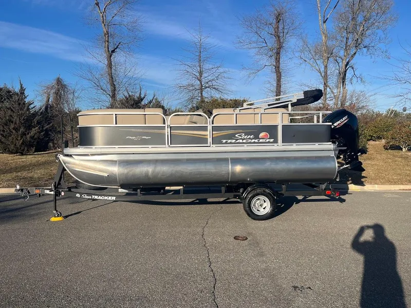 The Image of 2025 Sun Tracker Party Barge 18 DLX pontoon boat on trailer, parked outdoors. - 0