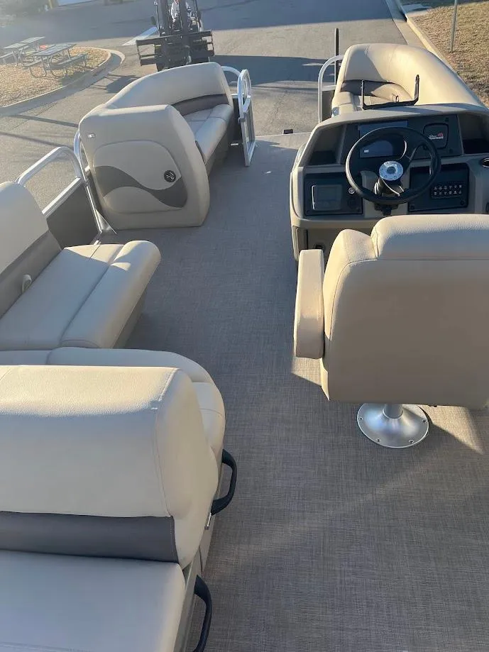 Slide: The Image of 2025 Sun Tracker Party Barge 18 DLX interior with beige seating and steering console. - 2