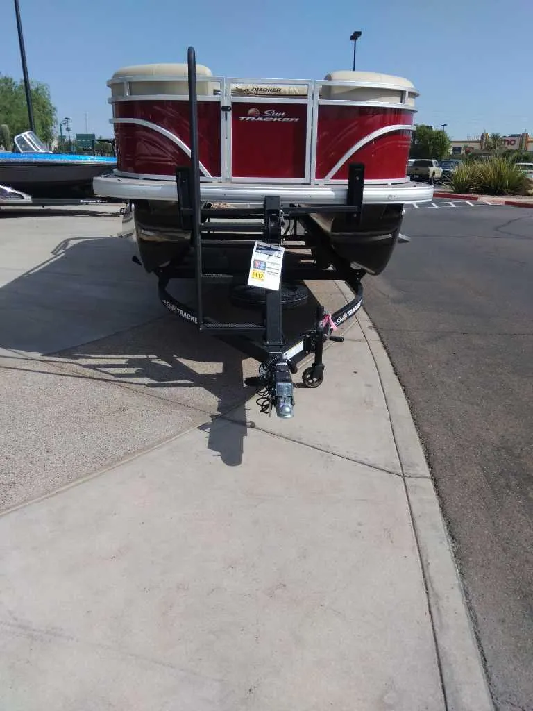 Slide: The Image of 2025 Sun Tracker Party Barge 22 RF DLX on trailer, parked on pavement. - 2