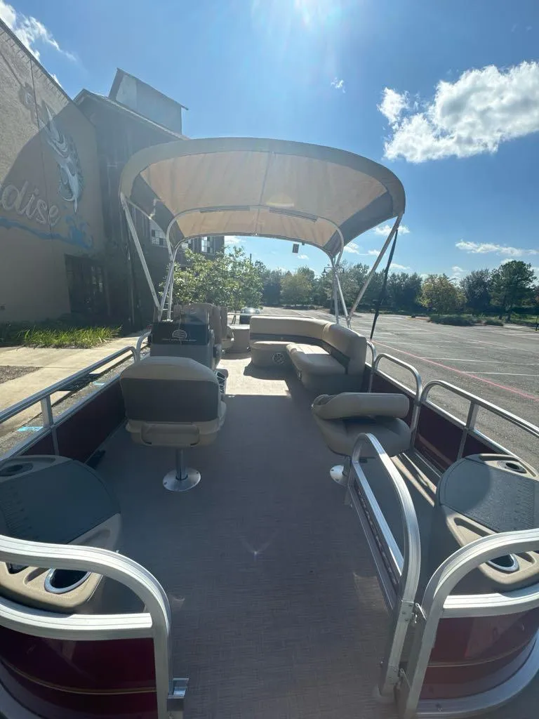 Slide: The Image of 2025 Sun Tracker Bass Buggy 18 DLX pontoon boat with canopy in sunny outdoor setting. - 4