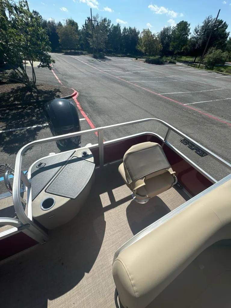 Slide: The Image of 2025 Sun Tracker Bass Buggy 18 DLX pontoon boat in parking lot, sunny day. - 5