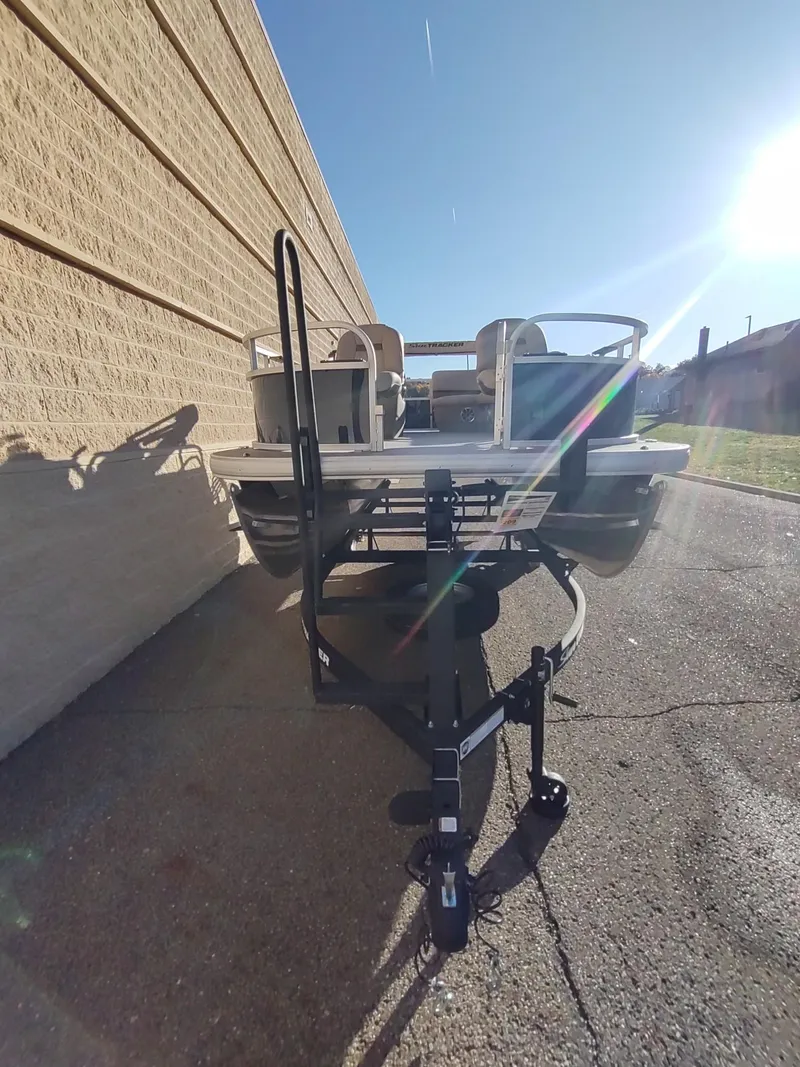 Slide: The Image of 2025 Sun Tracker Bass Buggy 16 XL Select pontoon boat on trailer, sunny day. - 2