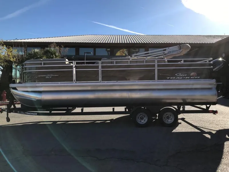 Slide: The Image of 2025 Sun Tracker SportFish 22 DLX pontoon boat on trailer, parked outdoors. - 7