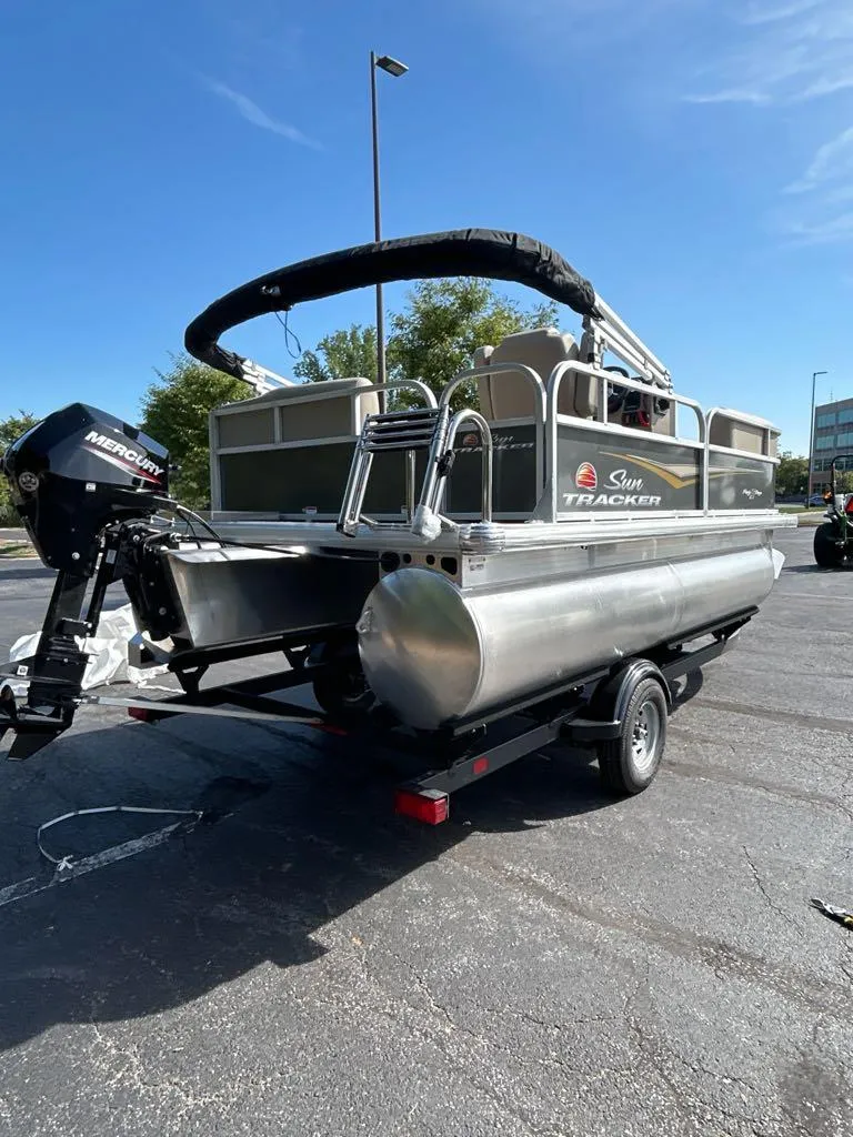 Slide: The Image of 2025 Sun Tracker Party Barge 16 DLX pontoon boat on trailer, outdoor setting. - 2
