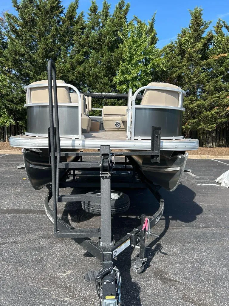 Slide: The Image of 2025 Sun Tracker Party Barge 16 DLX pontoon boat on trailer, parked outdoors. - 3