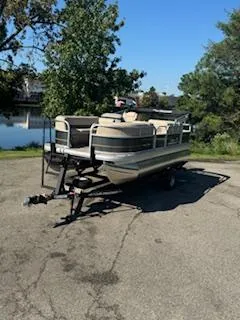 Slide: The Image of 2025 Sun Tracker Party Barge 18 DLX pontoon boat on trailer, parked near a lake. - 15