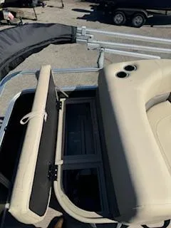 Slide: The Image of 2025 Sun Tracker Party Barge 18 DLX with open storage compartment and beige seating. - 7