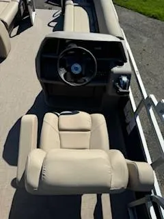 Slide: The Image of 2025 Sun Tracker Party Barge 18 DLX interior with beige seating and steering console. - 8