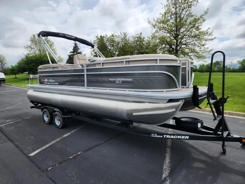 The Image of 2025 Sun Tracker Party Barge 22 RF DLX pontoon boat on trailer in parking lot. - 0