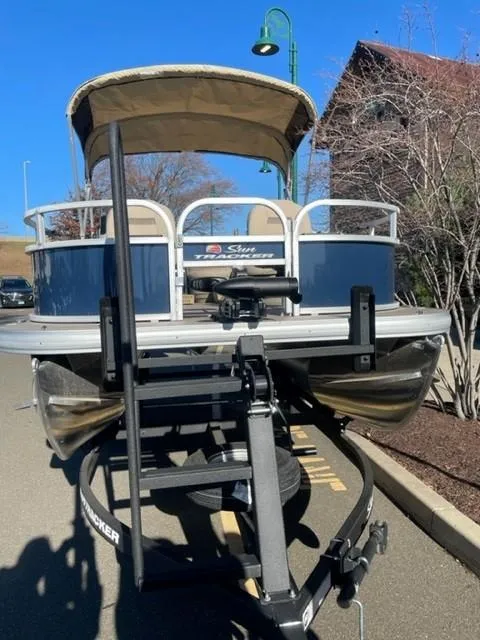 Slide: The Image of 2025 Sun Tracker Bass Buggy 16 XL Select pontoon boat on trailer, parked outdoors. - 3