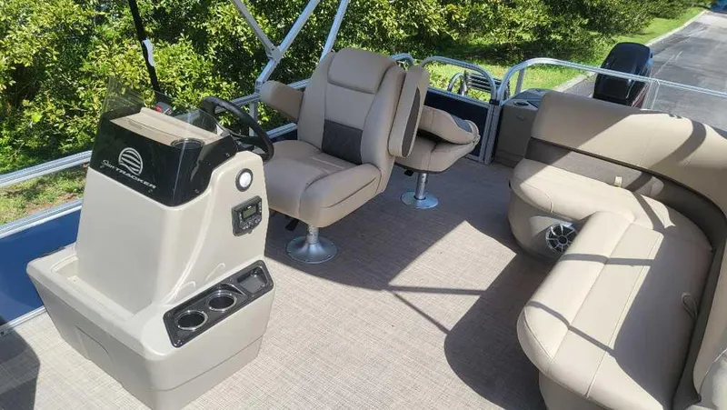 Slide: The Image of 2025 Sun Tracker Bass Buggy 18 DLX pontoon boat interior with beige seating and steering console. - 3