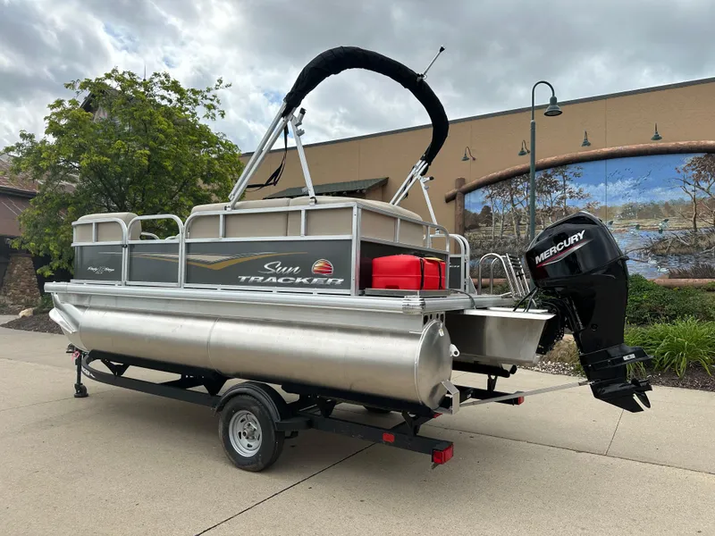 Slide: The Image of 2025 Sun Tracker Party Barge 16 DLX pontoon boat on trailer, outdoor display. - 2