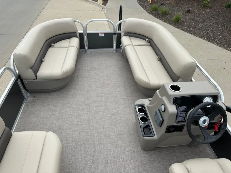 Slide: The Image of 2025 Sun Tracker Party Barge 16 DLX interior with beige seating and steering console. - 5