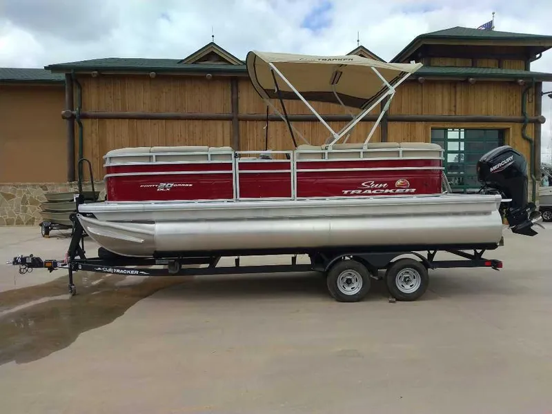 The Image of 2025 Sun Tracker Party Barge 20 DLX pontoon boat on trailer, parked outdoors. - 0