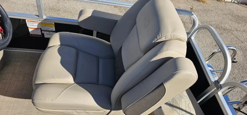 Slide: The Image of 2025 Sun Tracker Party Barge 16 DLX boat seat, beige upholstery, armrests, outdoor setting. - 15