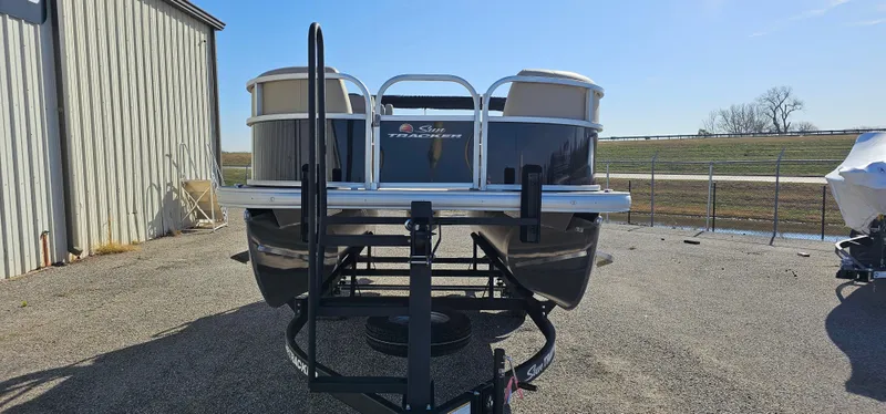 Slide: The Image of 2025 Sun Tracker Party Barge 16 DLX pontoon boat on trailer, parked outdoors. - 2