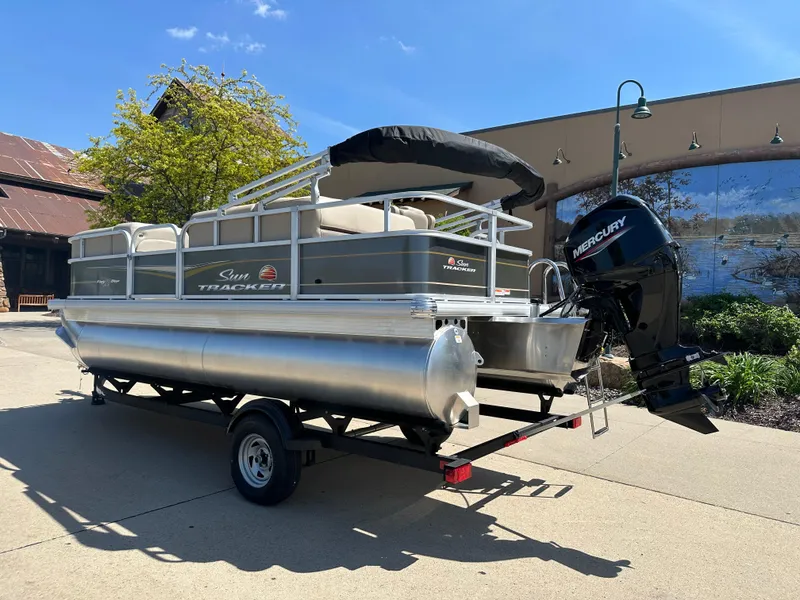 Slide: The Image of 2025 Sun Tracker Party Barge 18 DLX pontoon boat on trailer, outdoor setting. - 2