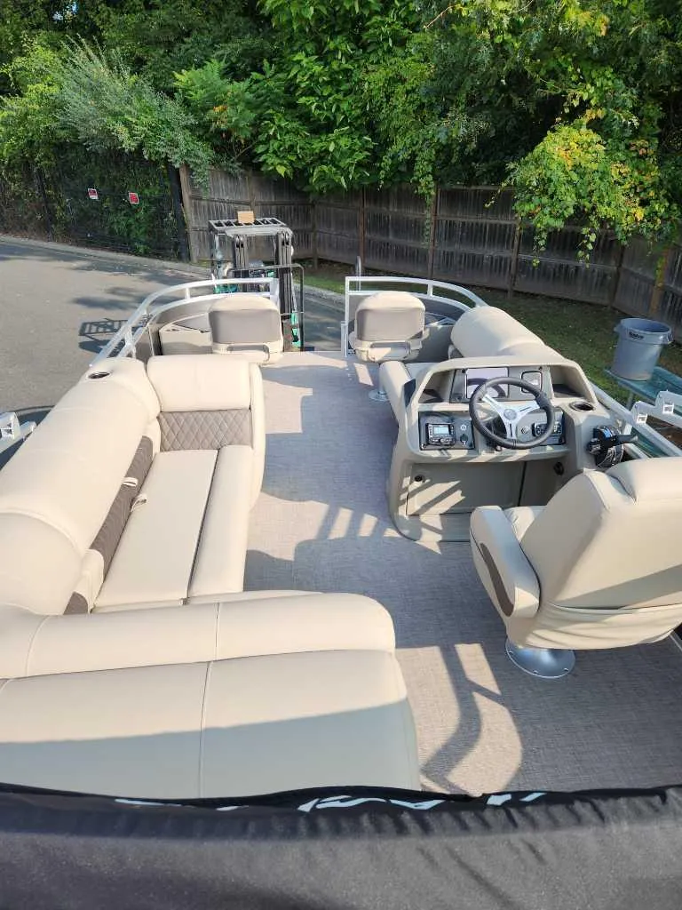 Slide: The Image of 2025 Sun Tracker Fishin' Barge 20 DLX interior with beige seating and steering console. - 3