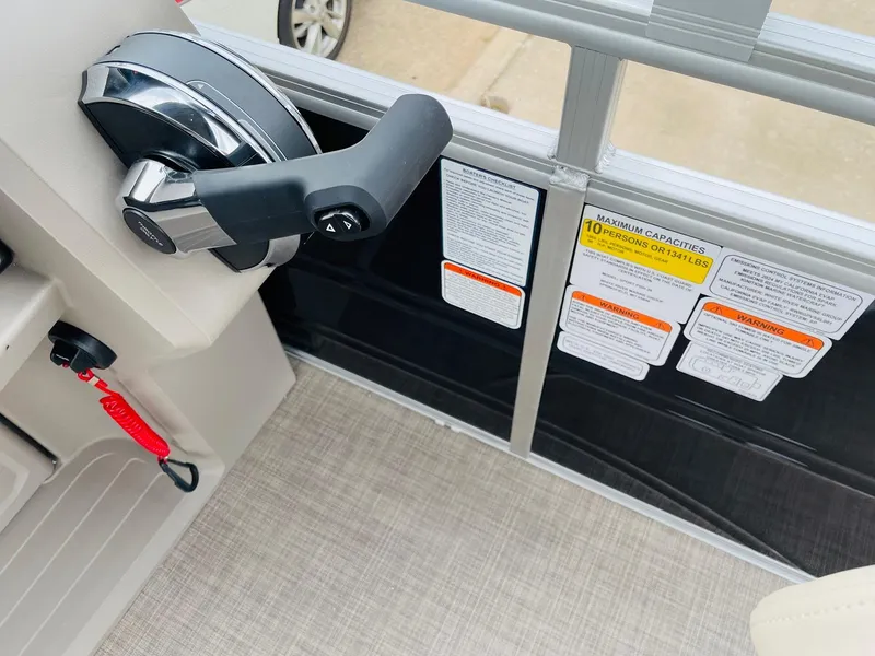 Slide: The Image of 2025 Sun Tracker SportFish 20 DLX boat controls with safety labels and throttle lever. - 28