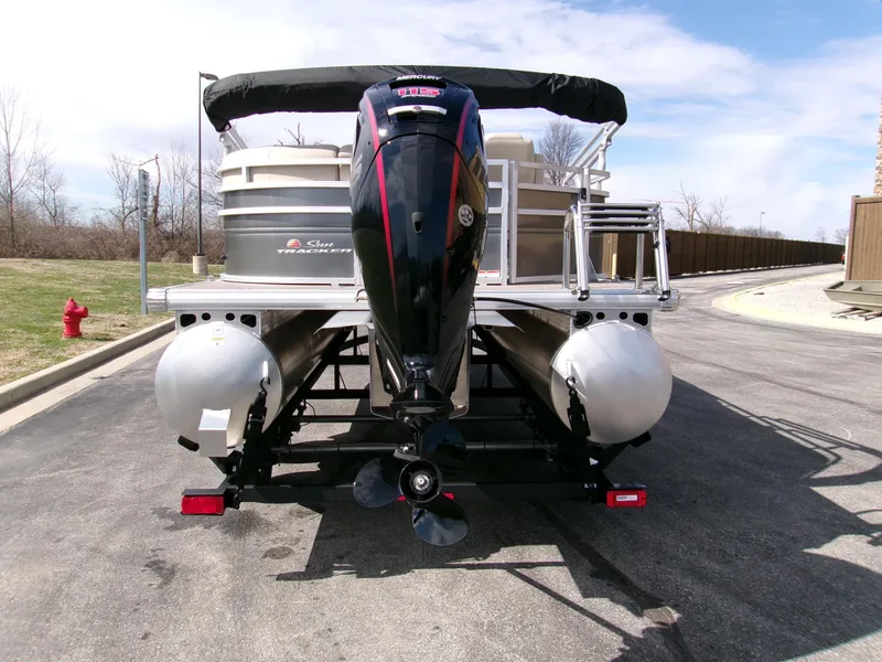 Slide: The Image of 2025 Sun Tracker Party Barge 20 DLX pontoon boat with outboard motor, parked on a trailer. - 3