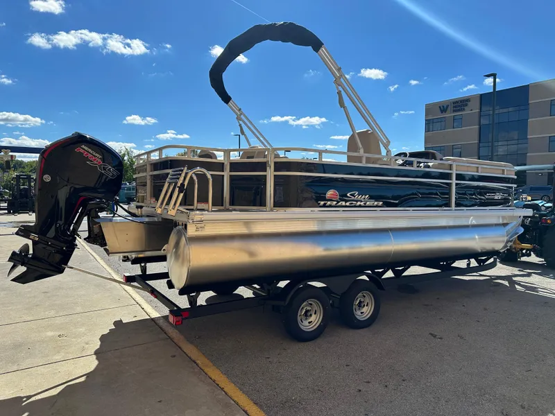 Slide: The Image of 2025 Sun Tracker SportFish 22 DLX pontoon boat on trailer, parked outdoors. - 2