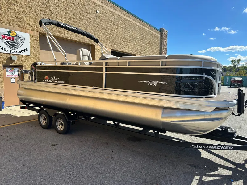 Slide: The Image of 2025 Sun Tracker SportFish 22 DLX pontoon boat on trailer, parked outdoors. - 3