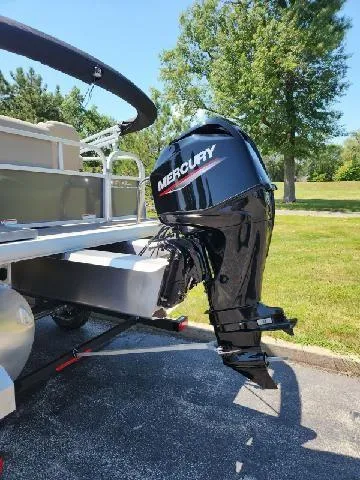 Slide: The Image of 2025 Sun Tracker Party Barge 16 DLX with Mercury outboard motor, parked on a sunny day. - 2