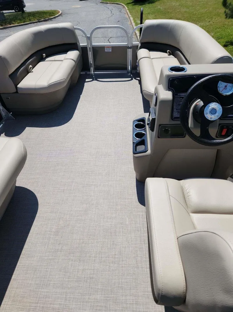 Slide: The Image of 2025 Sun Tracker Party Barge 16 DLX interior with beige seating and steering console. - 5