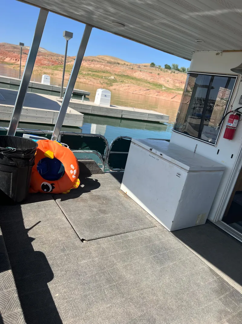 Slide: The Image of 2002 Sharpe houseboat deck with inflatable toy and freezer, docked by a scenic lake. - 11