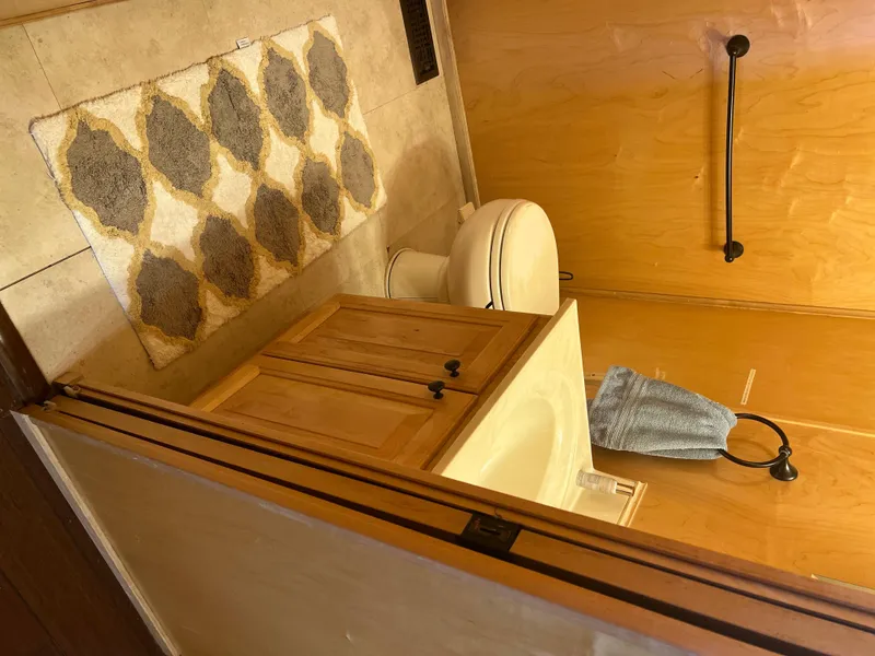 Slide: The Image of Bathroom interior of a 2002 Sharpe houseboat with wooden cabinets and patterned rug. - 22