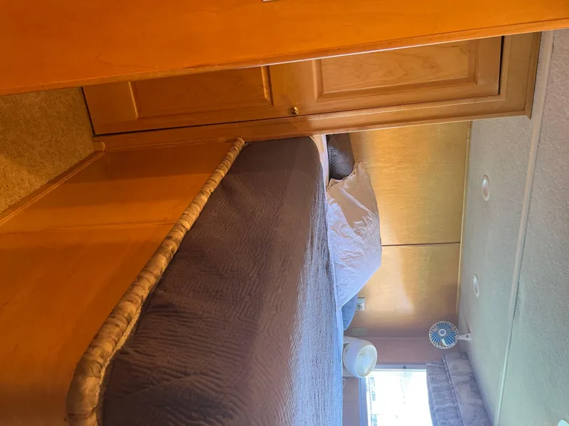 Slide: The Image of Interior of a 2002 Sharpe houseboat bedroom with wooden cabinetry and a cozy bed. - 23