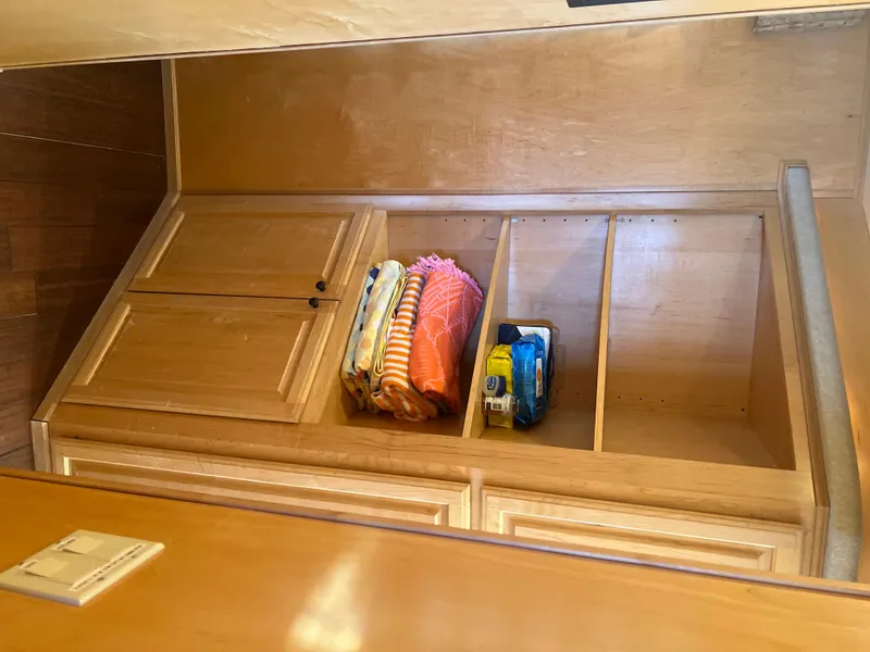 Slide: The Image of Wooden storage shelves in a 2002 Sharpe houseboat, featuring towels and supplies. - 25
