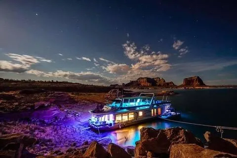 Slide: The Image of 2002 Sharpe houseboat illuminated at night on a serene lake with rocky landscape. - 3