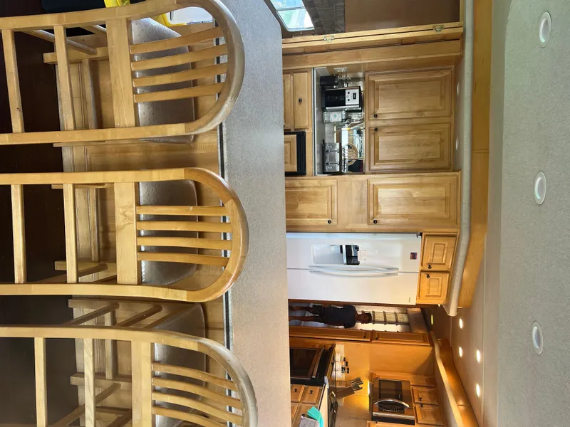 Slide: The Image of Interior of a 2002 Sharpe houseboat kitchen with wooden cabinets and bar stools. - 31
