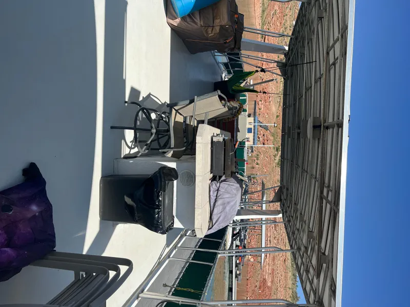 Slide: The Image of 2002 Sharpe houseboat deck with chairs, table, and covered roof, docked by rocky shoreline. - 43