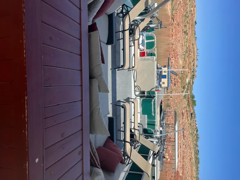Slide: The Image of 2002 Sharpe houseboat with outdoor seating, docked near rocky shoreline under clear blue sky. - 47