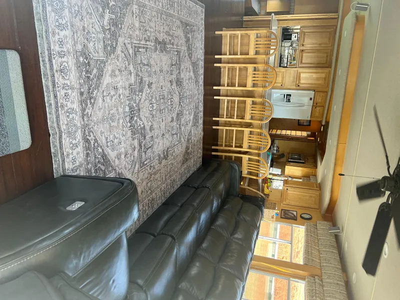Slide: The Image of Interior of 2002 Sharpe houseboat with leather sofa, patterned rug, and wooden kitchen area. - 9