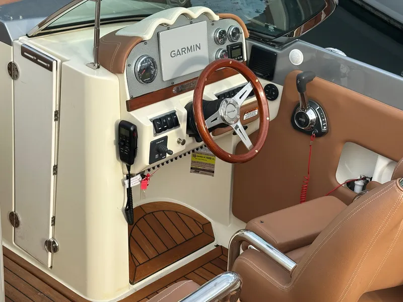 Slide: The Image of 2013 Chris-Craft Launch 25 boat dashboard with Garmin navigation and wooden steering wheel. - 2