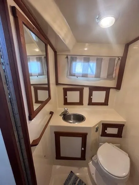 Slide: The Image of 1989 Blue Seas Out Island Explorer yacht bathroom with sink, toilet, and wooden cabinetry. - 40