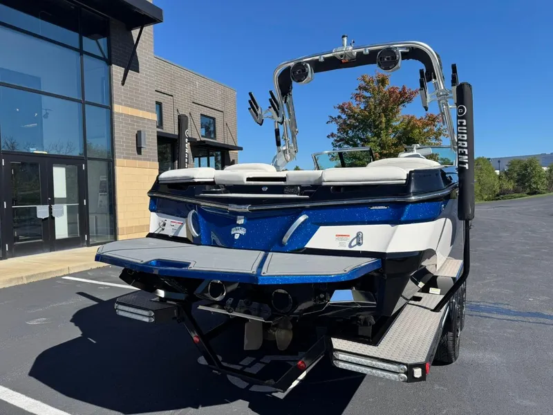 Slide: The Image of 2019 MasterCraft XT23 boat, blue and white, parked outdoors near a building. - 4