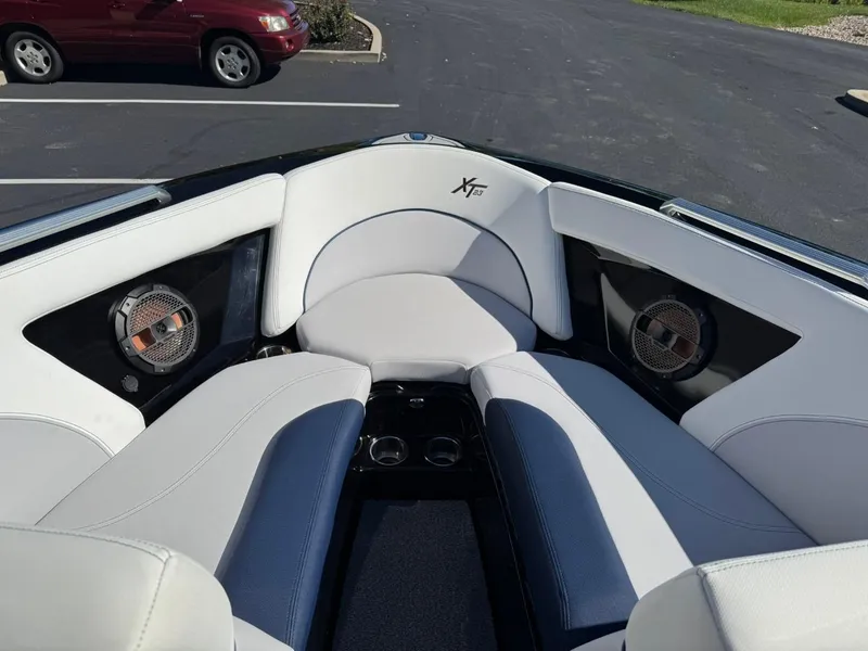 Slide: The Image of 2019 MasterCraft XT23 boat interior with white and blue seating, speakers, and cup holders. - 8
