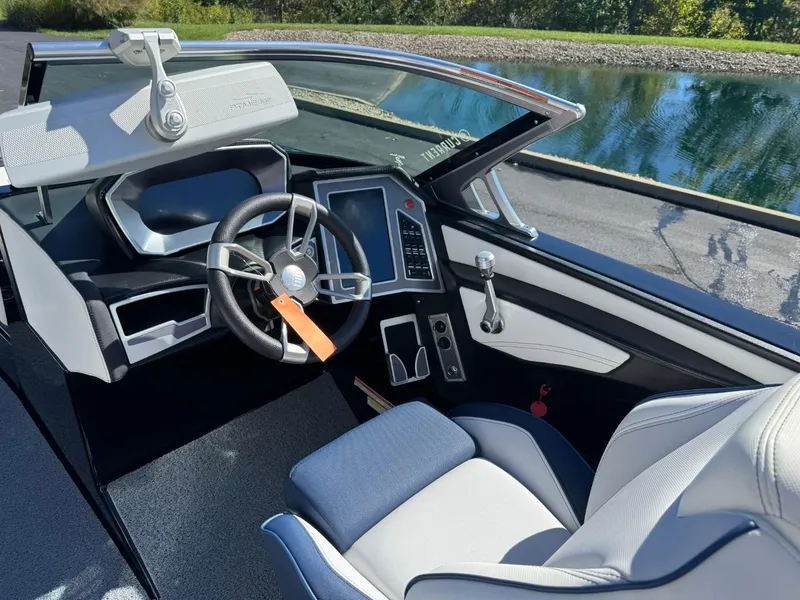 Slide: The Image of 2019 MasterCraft XT23 boat cockpit with modern steering and controls by a lake. - 9