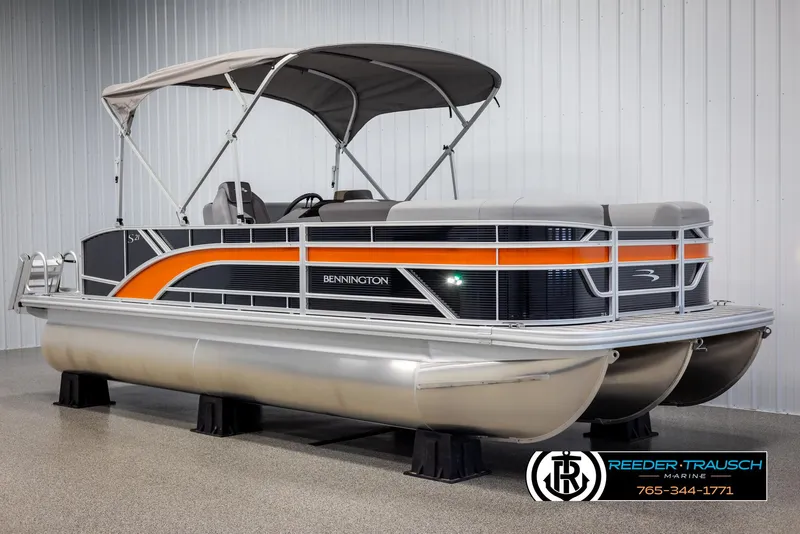 Slide: The Image of 2025 Bennington 21 SSBSE pontoon boat with orange and black accents in showroom. - 3